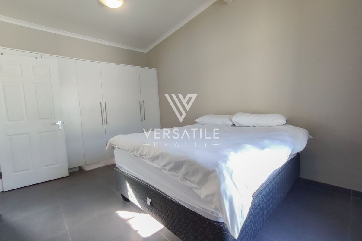 A bedroom featuring built-in cupboards, tiled flooring, and a vaulted ceiling with a central light fixture.