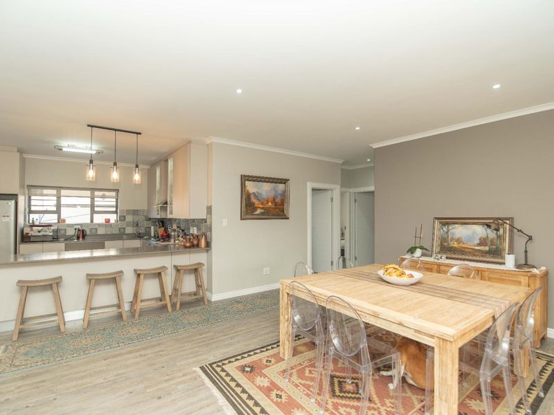 An open-plan living and dining area featuring a modern kitchen with a breakfast bar, neutral wall tones, and durable laminate flooring throughout.