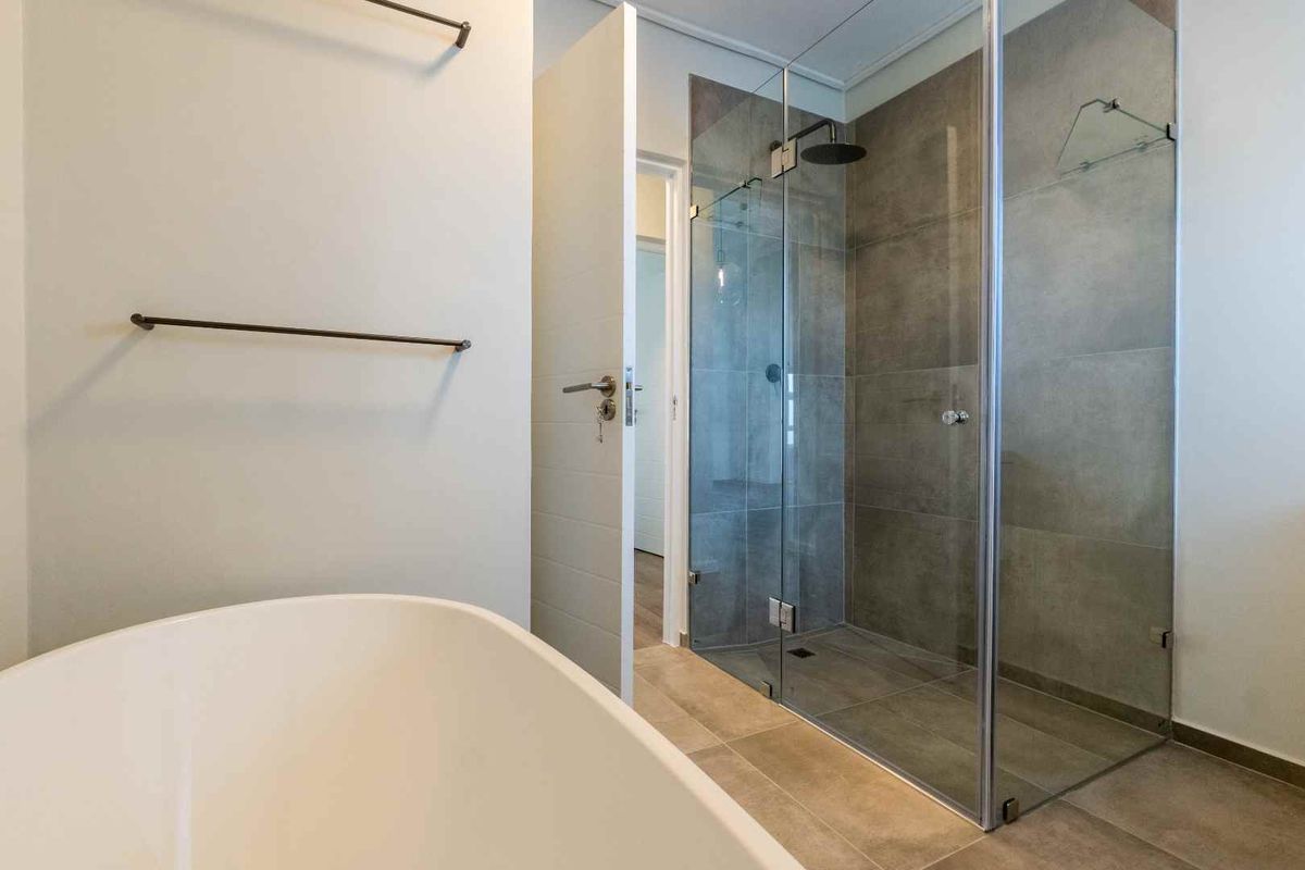 Modern bathroom featuring a sleek walk-in shower with glass enclosure, rain shower head, and a contemporary freestanding bathtub.