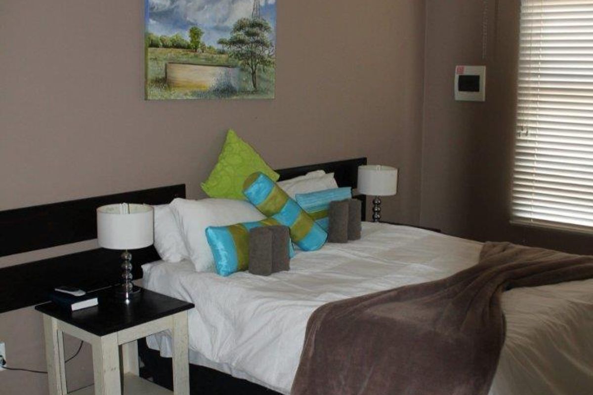 A bedroom featuring tiled flooring, a ceiling fan, and a wall-mounted air conditioning unit.