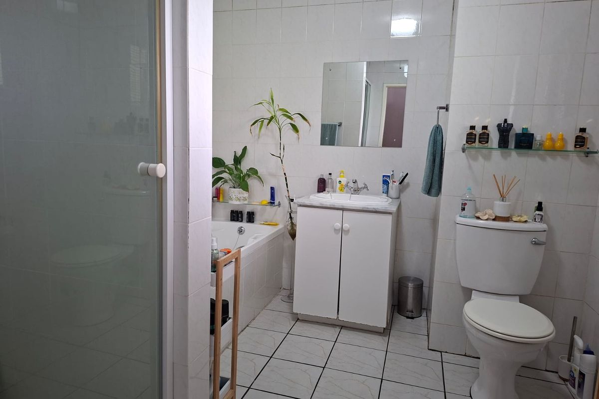 A functional bathroom featuring a built-in vanity, bathtub, shower enclosure, and tiled finishes throughout.