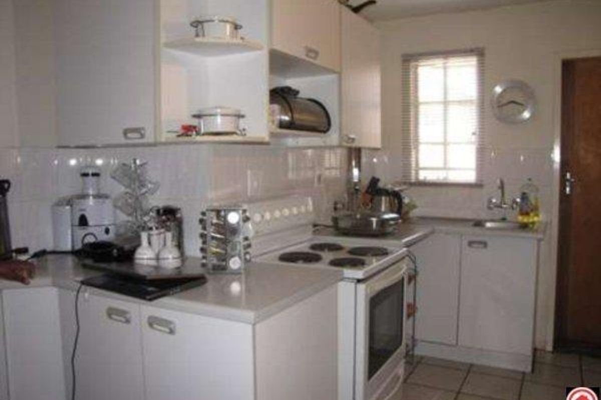 A functional kitchen featuring white built-in cabinetry, an electric stove with oven, tiled backsplash, and a stainless steel sink with tiled flooring.