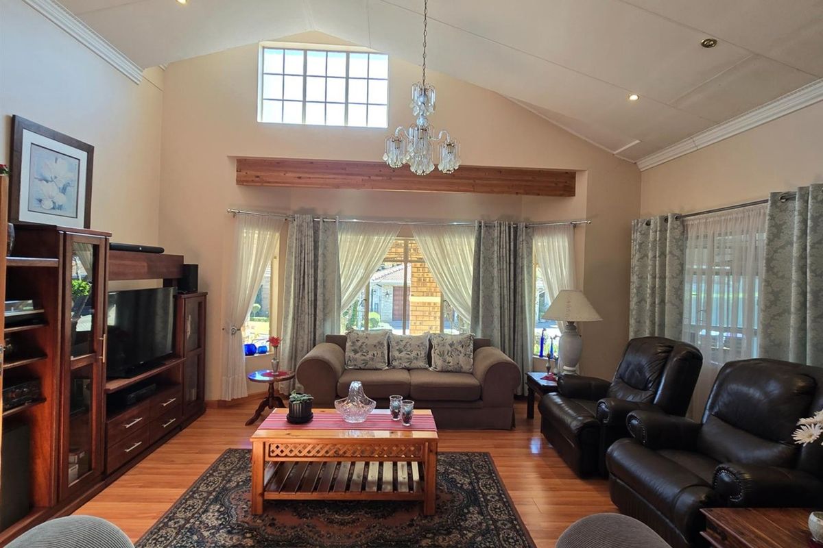 Spacious living room featuring a high vaulted ceiling with exposed timber beam, timber flooring, and a large clerestory window providing natural light.