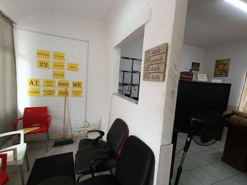 Office reception area featuring painted brick walls, a pass-through window, and tiled flooring, currently used as a waiting area.