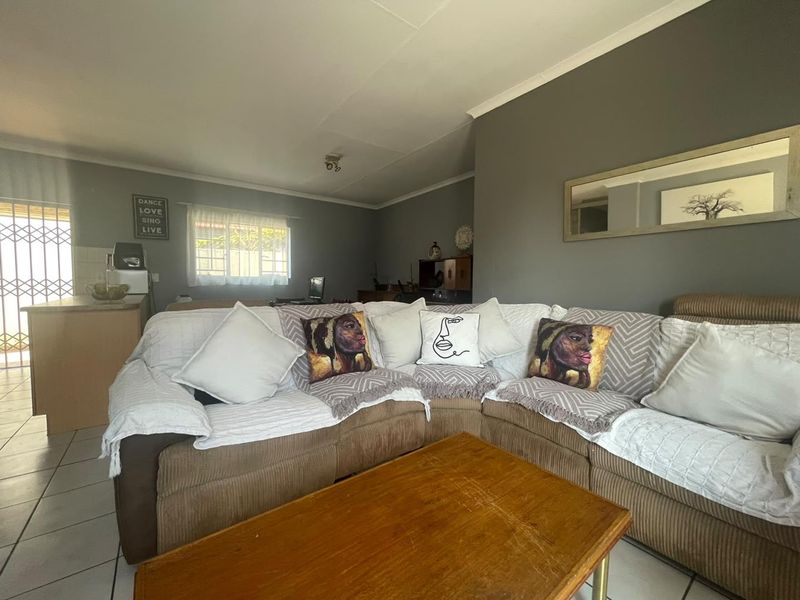 Open plan living area featuring tiled flooring and direct access to an exterior security gate, seamlessly connecting to the kitchen space.
