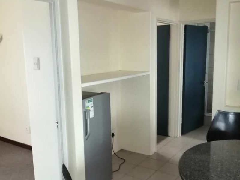 A functional hallway area featuring tiled flooring, recessed shelving, and integrated ceiling lighting, providing access to adjacent rooms.