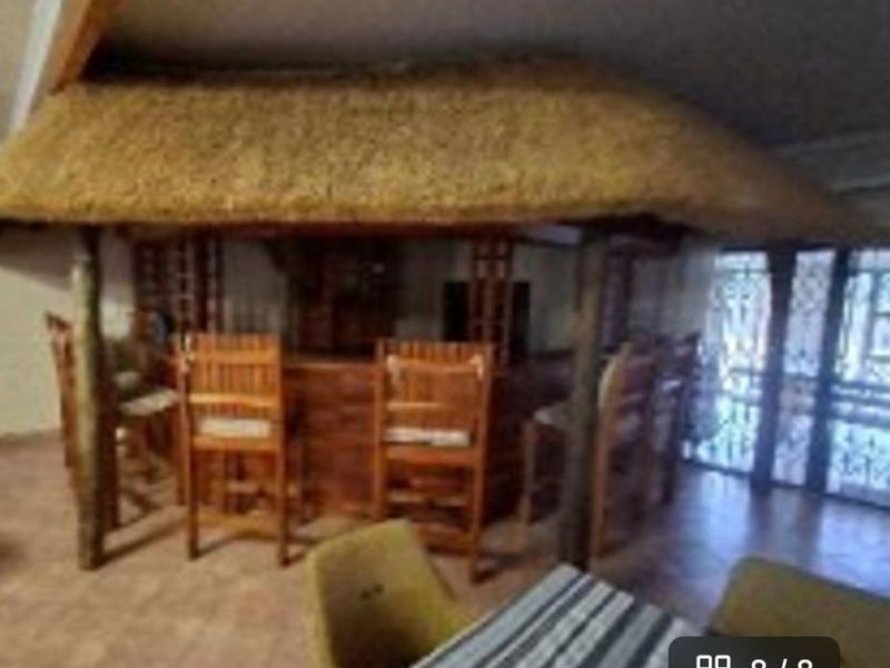 Indoor entertainment area featuring a built-in bar with a traditional thatched roof design and timber support posts.