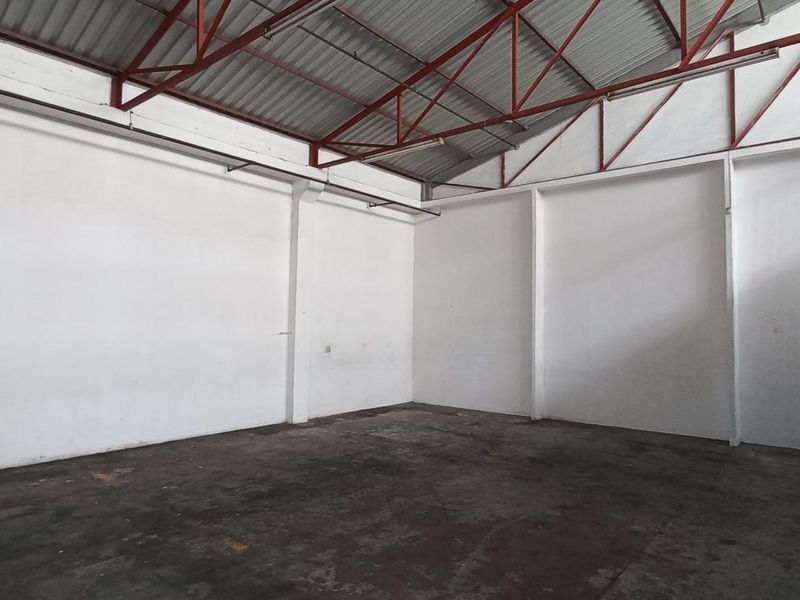 Spacious industrial utility area featuring high ceilings with exposed steel trusses, concrete flooring, and an integrated metal staircase.