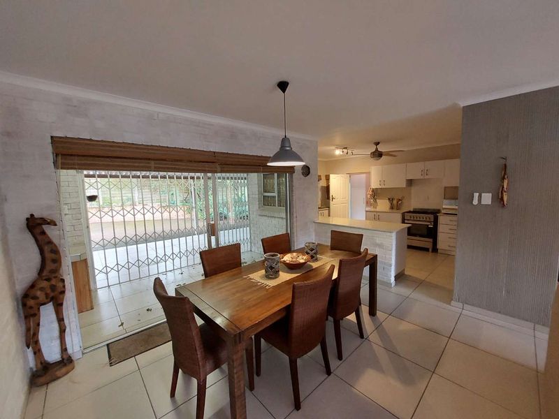 Open-plan dining and kitchen area featuring tiled floors, a breakfast bar, and direct access to a covered patio through sliding glass doors.