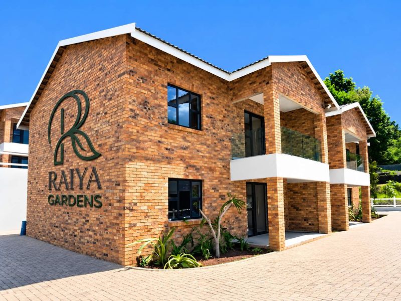 Modern townhouse exterior featuring face brick construction, glass balustrades, and paved driveway access at Raiya Gardens.