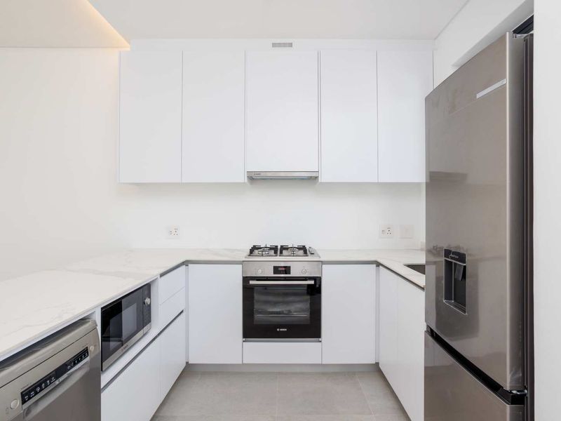 Modern kitchen featuring sleek white cabinetry, stone countertops, high-quality built-in appliances, and a clean, minimalist aesthetic.