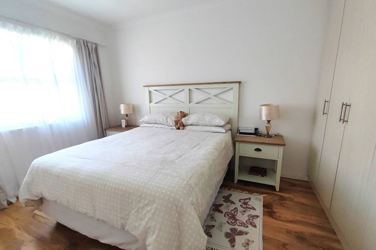 A well-maintained bedroom featuring laminate flooring, neutral walls, and a built-in wardrobe, offering a clean and functional living space.