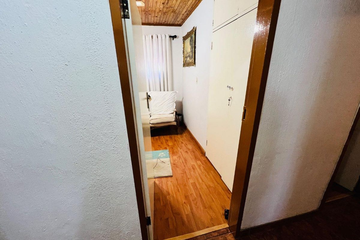 A bedroom featuring timber ceiling paneling, built-in cupboards, and wood-look flooring, viewed from the hallway entrance.