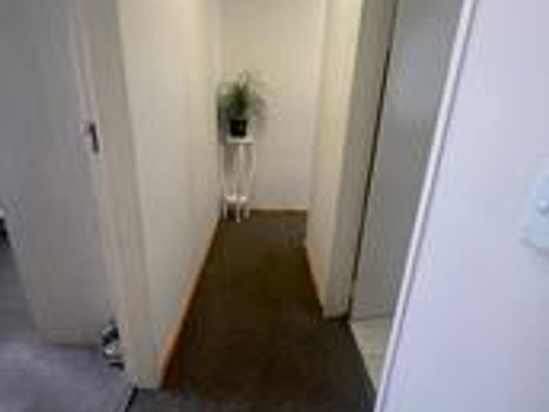 A simple, functional hallway connecting interior spaces, featuring neutral wall finishes and carpeted flooring.