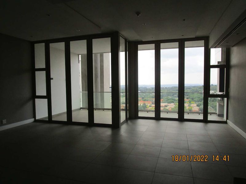 Spacious open-plan living area featuring large floor-to-ceiling glass doors that provide abundant natural light and access to a private balcony with scenic views.