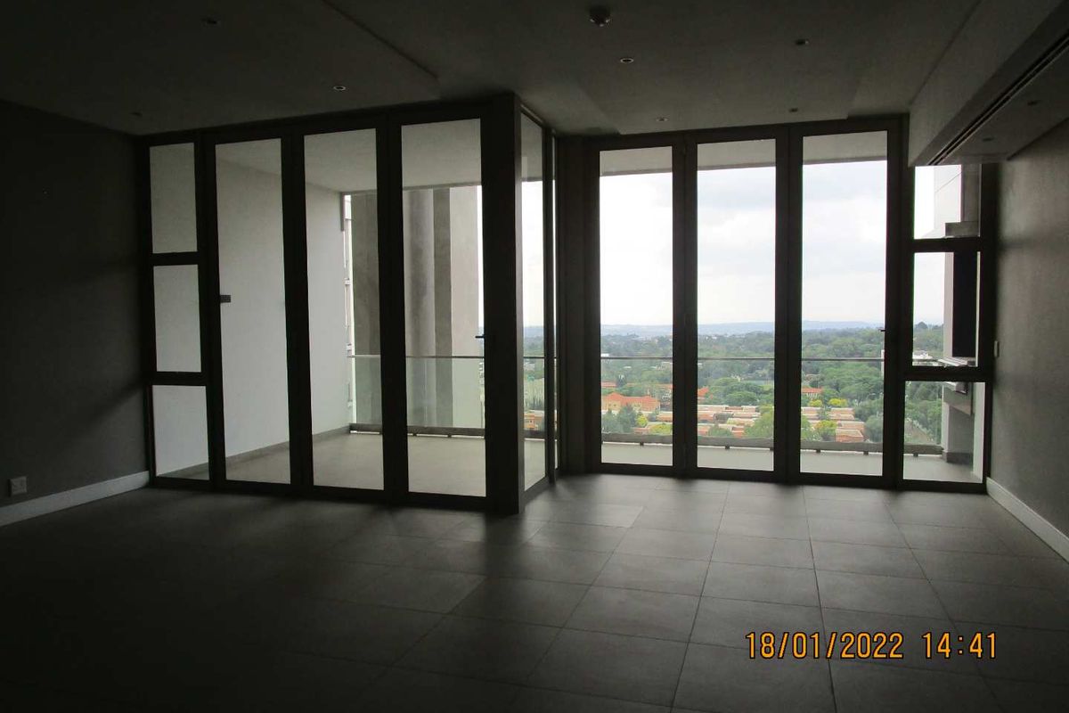 Spacious open-plan living area featuring large floor-to-ceiling glass doors that provide abundant natural light and access to a private balcony with scenic views.