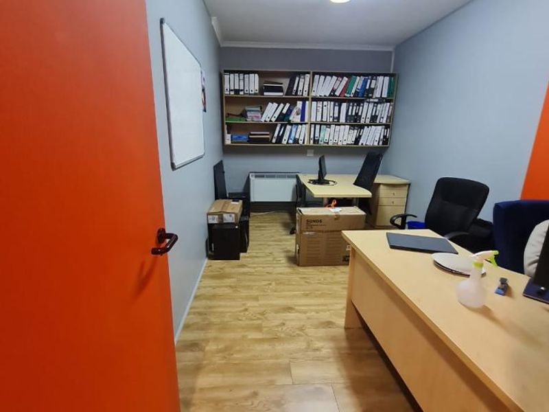 A functional office space featuring laminate flooring, built-in shelving, and bright overhead lighting, suitable for a productive work environment.
