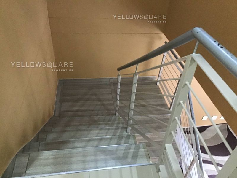 A staircase featuring tiled steps and a metal balustrade, connecting levels within the townhouse.