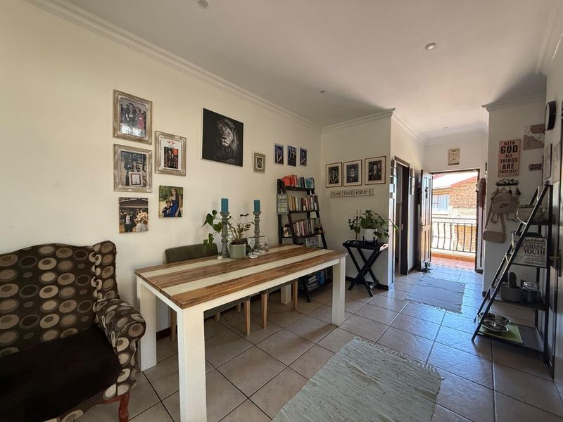 A living area featuring tiled flooring, decorative cornicing, and recessed lighting, with direct access to an outdoor balcony space.