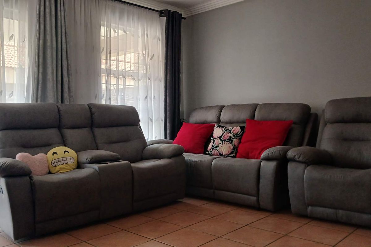 A living room area featuring tiled flooring and decorative ceiling cornicing, providing a neutral base for interior design.