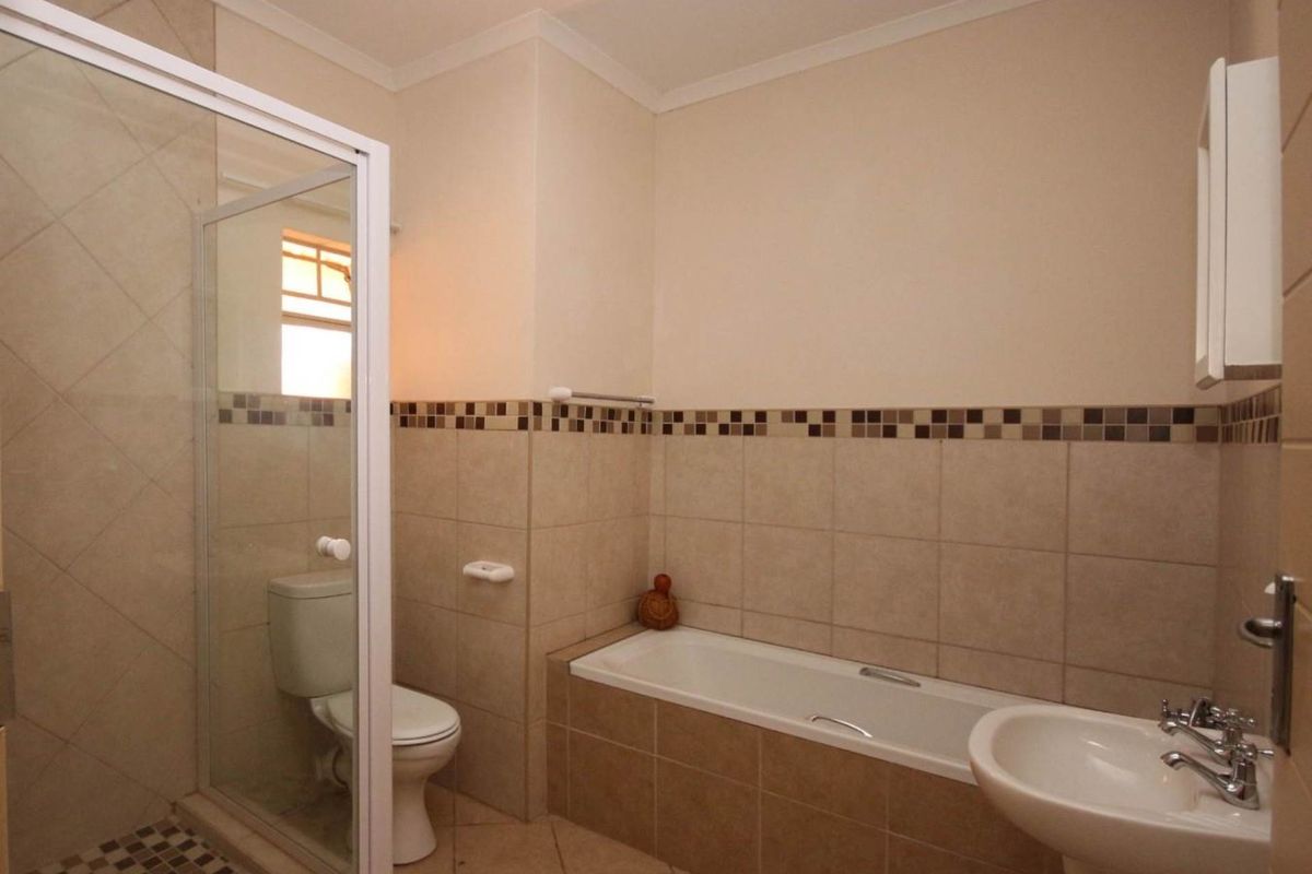 A clean and functional bathroom featuring a separate shower enclosure, bathtub, pedestal sink, and toilet with neutral tiled finishes.