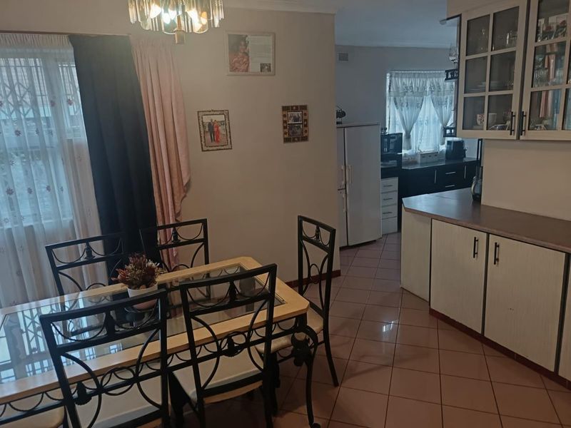 Open plan dining and kitchen area featuring tiled flooring and functional built-in cabinetry with laminate countertops.