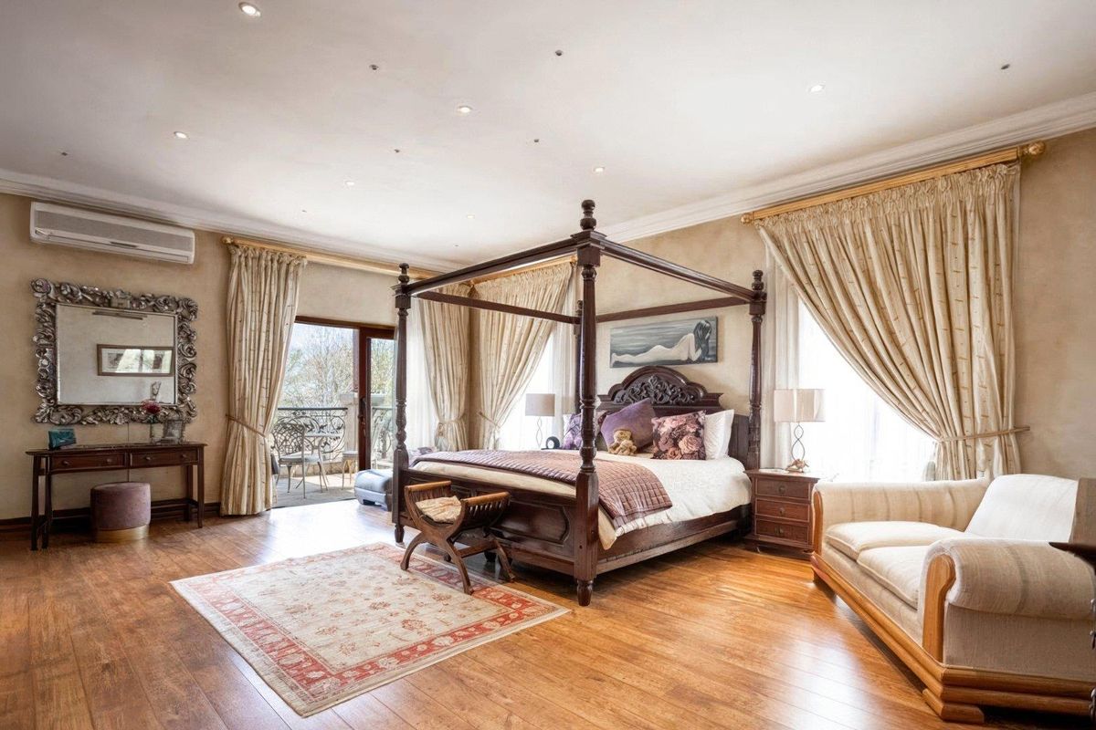 Spacious bedroom featuring hardwood flooring, recessed lighting, a wall-mounted air conditioning unit, and direct access to a private balcony.