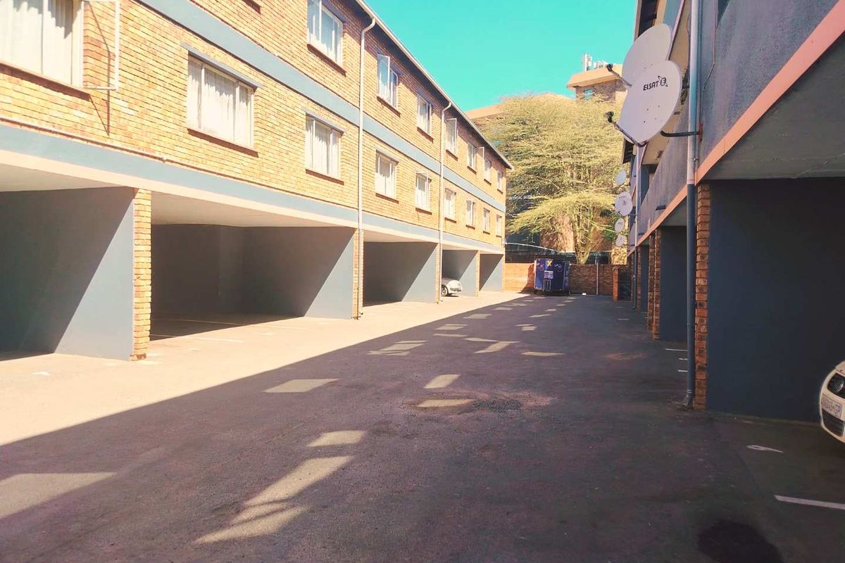 Exterior view of the apartment complex showing the ground level covered parking bays and brick facade.