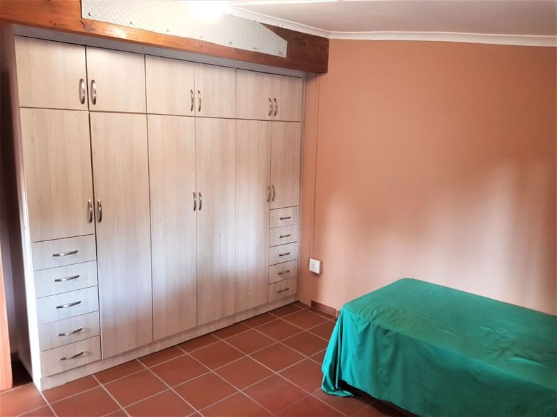 A bedroom featuring extensive built-in cabinetry with integrated drawers and tiled flooring, accented by a decorative timber beam.