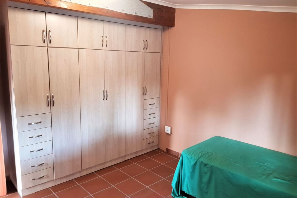 A bedroom featuring extensive built-in cabinetry with integrated drawers and tiled flooring, accented by a decorative timber beam.