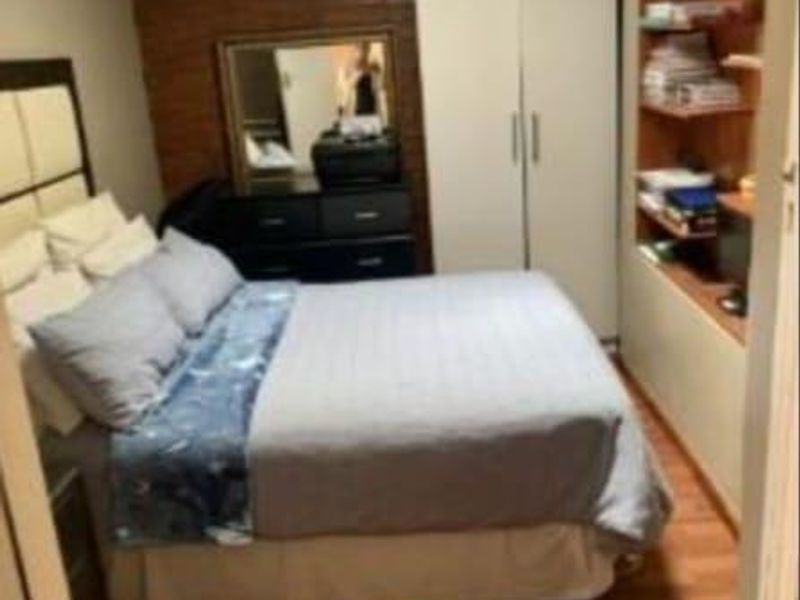 A bedroom featuring an exposed brick wall, built-in wardrobe, and integrated shelving with laminate flooring.