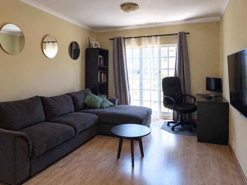 A comfortable living room featuring laminate flooring, a sliding glass door providing natural light, and neutral wall finishes.
