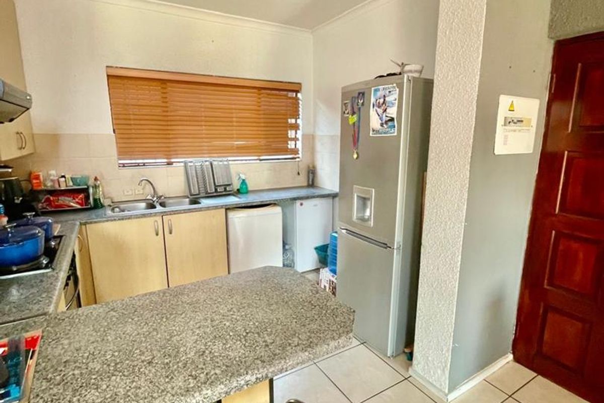 A functional kitchen featuring granite countertops, laminate cabinetry, a breakfast nook, and ceramic floor tiles, offering a practical layout for daily meal preparation.