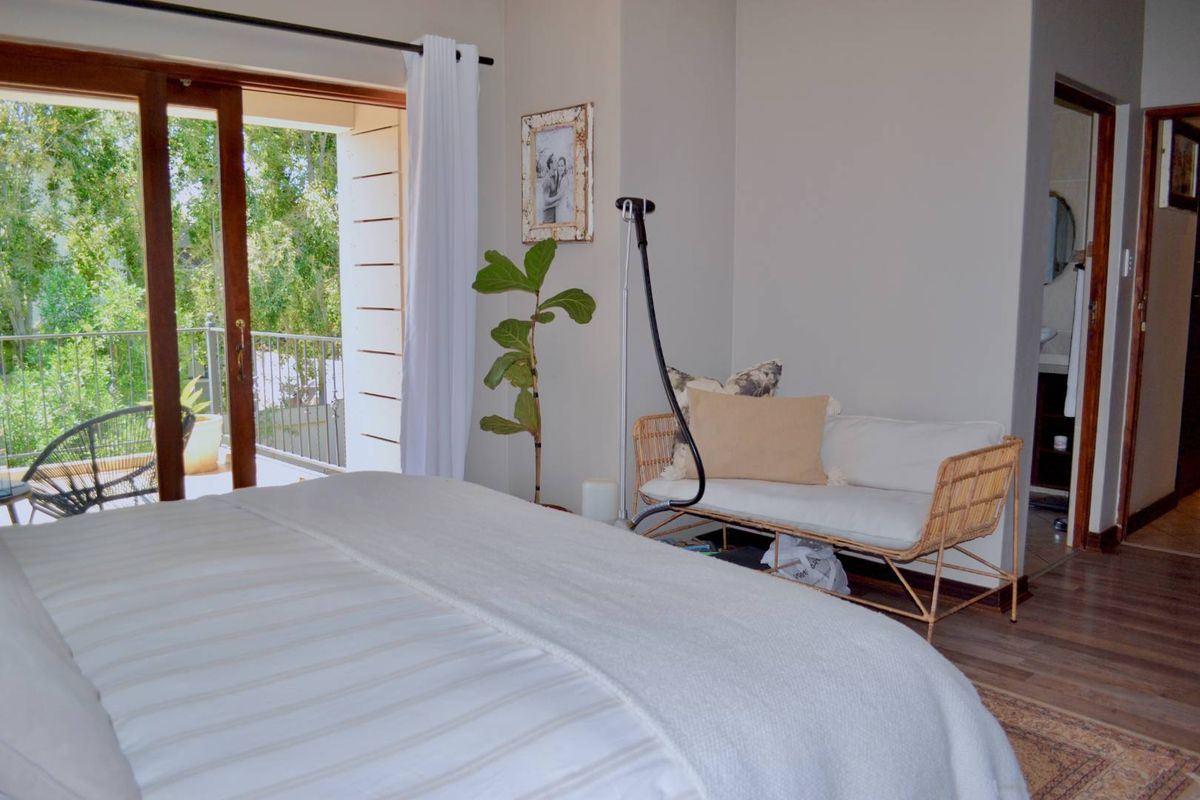 A well-lit bedroom featuring laminate flooring and a sliding glass door providing direct access to a private balcony.