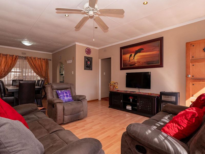 A comfortable living room featuring laminate flooring, a ceiling fan, and recessed lighting, with an open archway leading to the adjacent dining area.