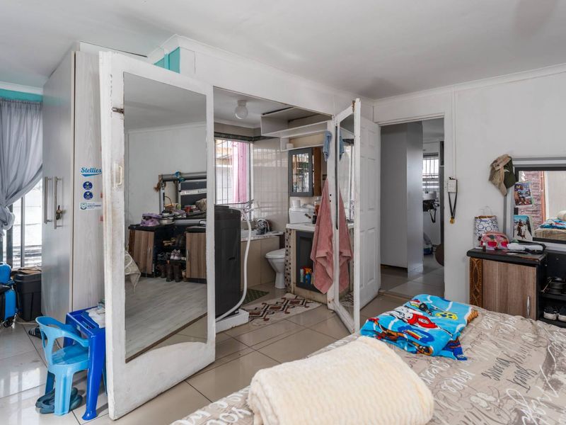 Bedroom featuring built-in cupboards with mirrored doors and an integrated en-suite bathroom with tiled flooring throughout.