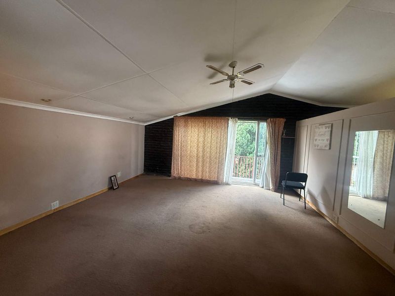 Spacious bedroom featuring a vaulted ceiling, ceiling fan, and direct access to a private balcony through sliding glass doors.