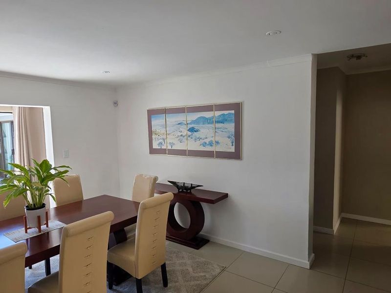 An open-plan dining area featuring tiled floors, recessed lighting, and a sliding glass door providing access to the outdoor space.