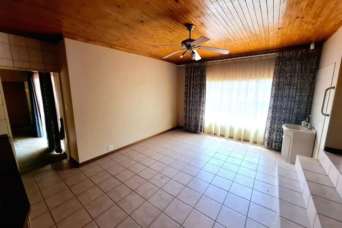 Spacious bedroom featuring a timber ceiling, ceiling fan, tiled flooring, and a built-in vanity basin with a safety grab rail.