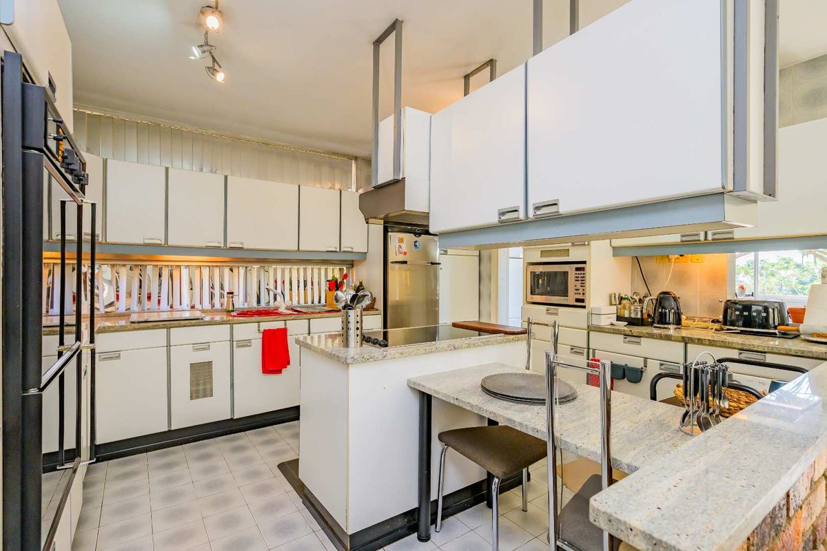 A functional kitchen featuring white cabinetry, granite countertops, a breakfast bar, and built-in appliances including an oven and microwave.