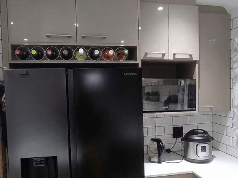 Modern kitchen featuring sleek high-gloss cabinetry, a subway tile backsplash, and integrated microwave, offering a clean and functional culinary space.