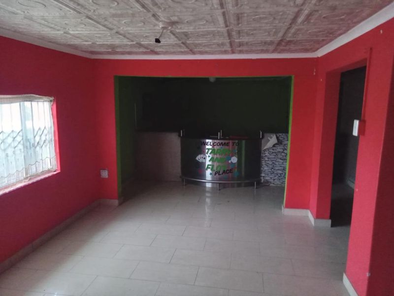 An empty bar area featuring tiled flooring, decorative ceiling tiles, and a built-in bar counter, ready for a modern update.