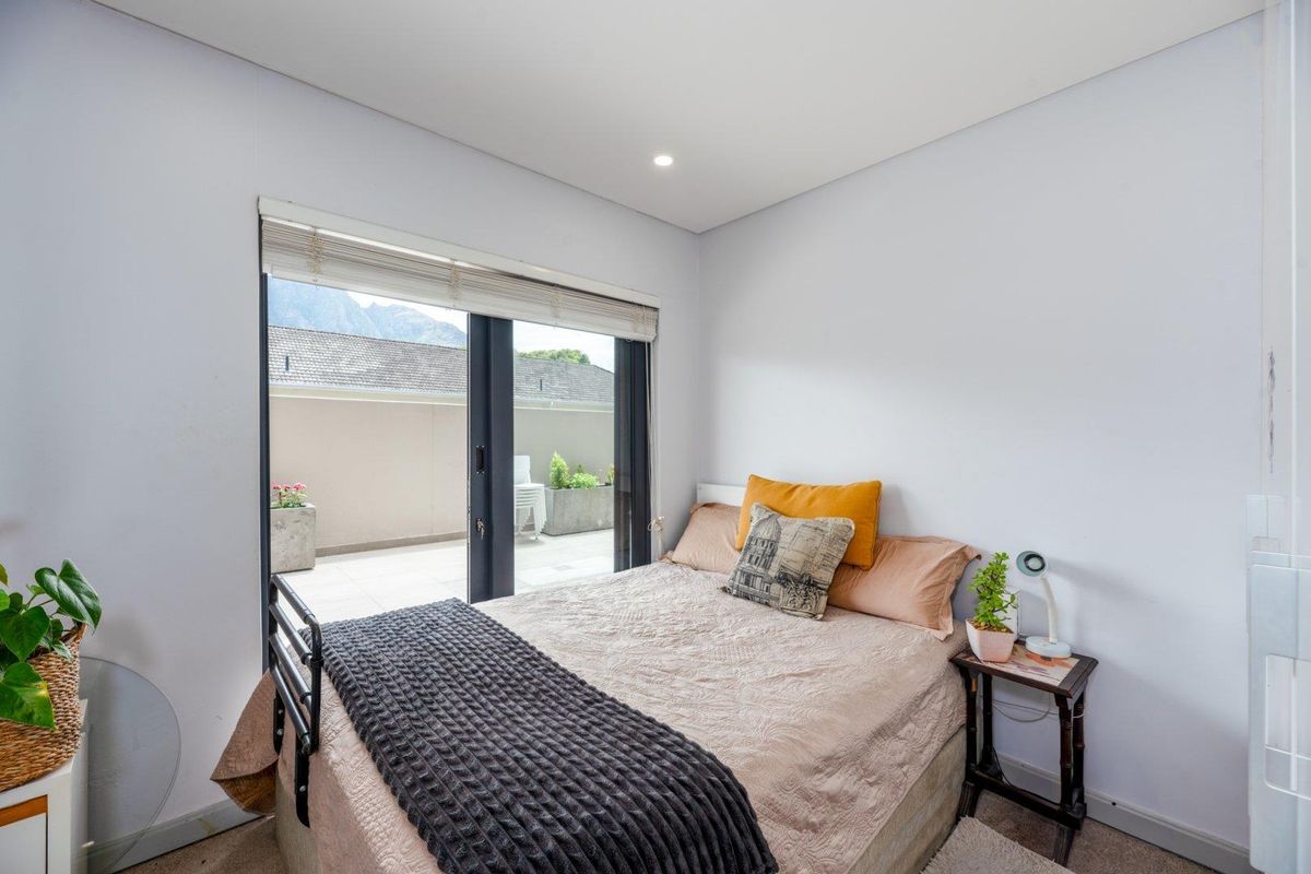 A bright bedroom featuring neutral walls, recessed lighting, and large sliding glass doors that provide direct access to an outdoor patio area.
