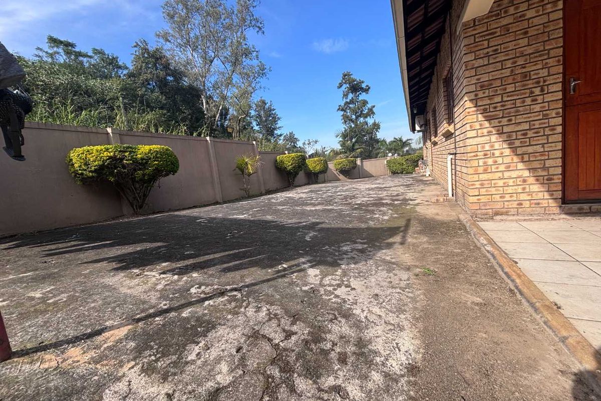 A rear exterior area featuring a large concrete paved space, perimeter boundary wall, and direct access to the townhouse structure.