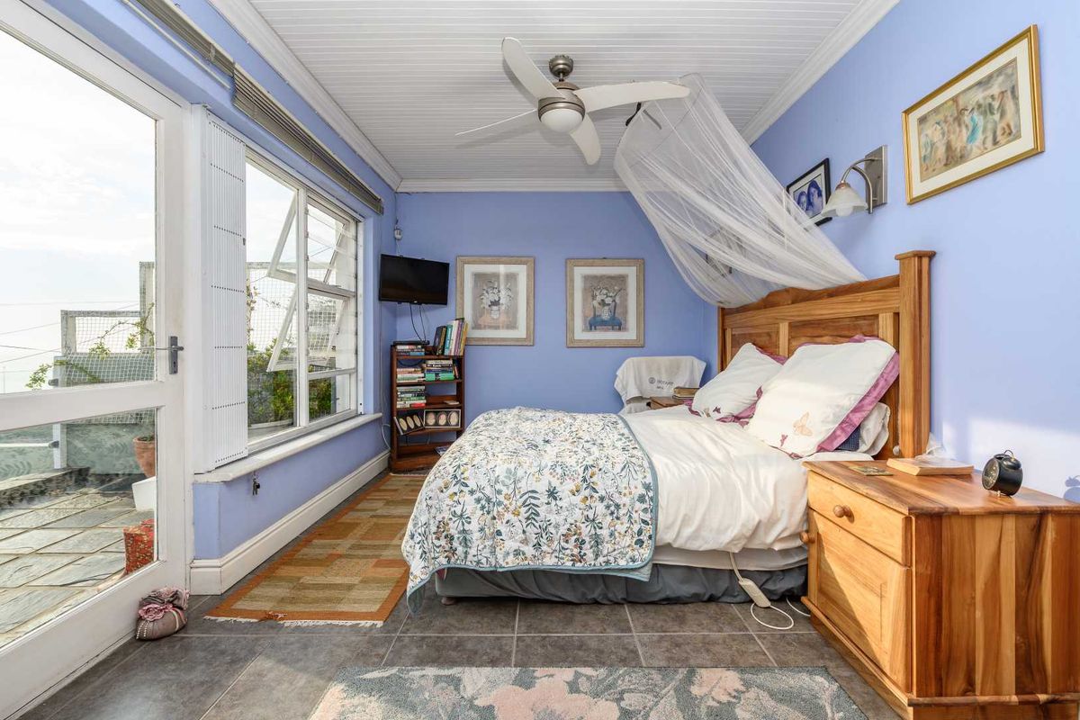 A bedroom featuring tiled flooring, a ceiling fan, and large windows with direct access to an outdoor patio area.
