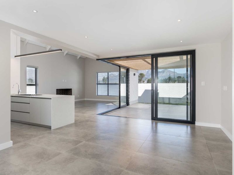 Modern open-plan living area featuring a sleek kitchen island, tiled floors, and large sliding doors that open to an outdoor patio space.