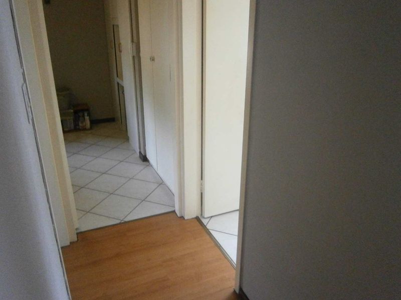 A functional hallway area featuring a mix of laminate and tiled flooring with built-in storage cupboards.
