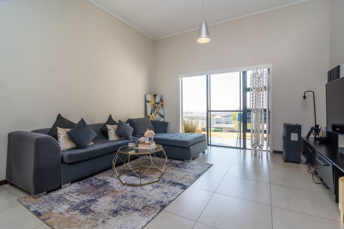 Spacious living room featuring large format floor tiles, high ceilings, and sliding glass doors providing access to the outdoor area.
