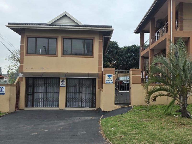 Front exterior view of the apartment building featuring a paved driveway, security gate, and perimeter wall with integrated security features.