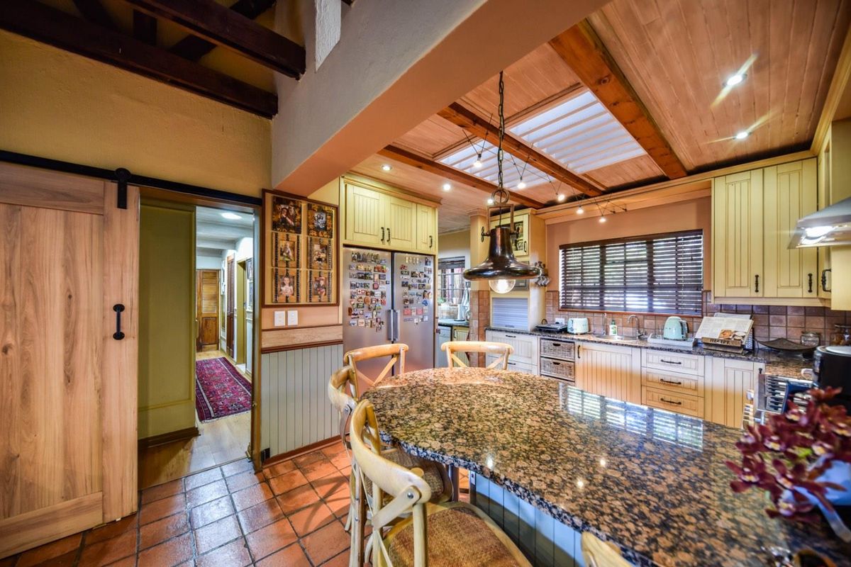 Spacious kitchen featuring granite countertops, timber ceiling with exposed beams, skylight, and a sliding barn door leading to the hallway.